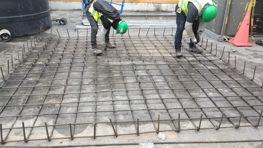 Personal revisando el armado de acero en una losa de obra civil